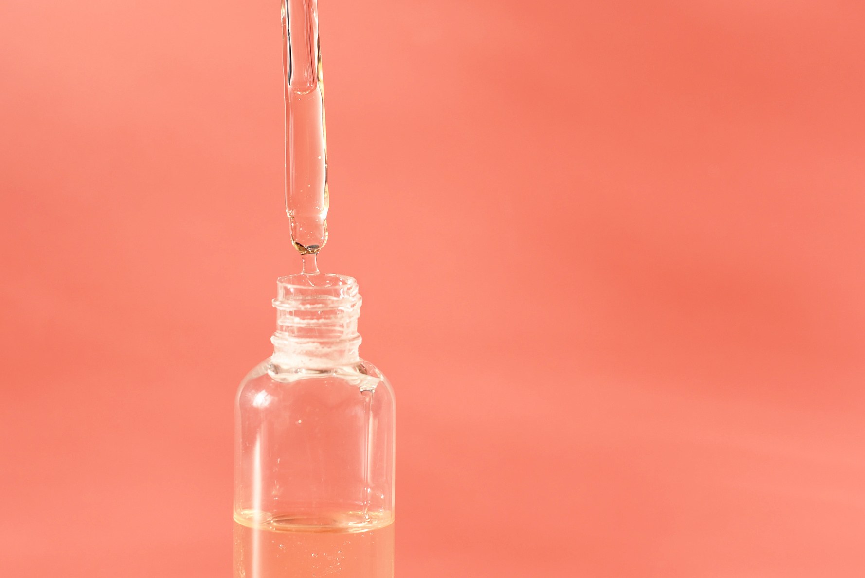 Natural Serums. Concept of cosmetic injection is hyaluronic acid, botulinum, serum. Cosmetic pipette with drops of cosmetic oil or liquid gel close-up on a pink background